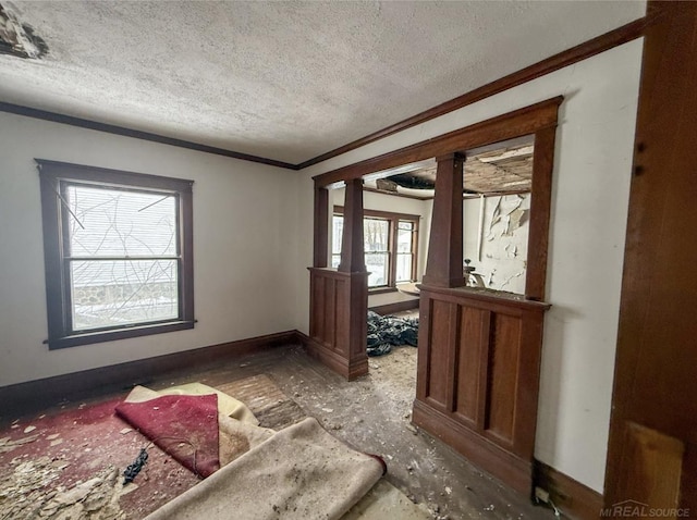 entrance foyer featuring ornamental molding, decorative columns, a textured ceiling, and baseboards