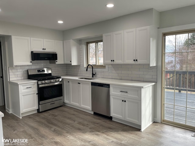 kitchen with light countertops, appliances with stainless steel finishes, light wood-style floors, white cabinetry, and a sink