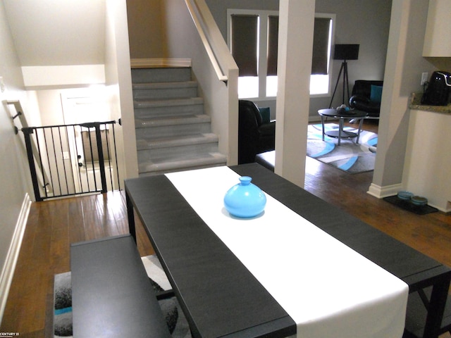 dining room with dark wood-type flooring, stairway, and baseboards