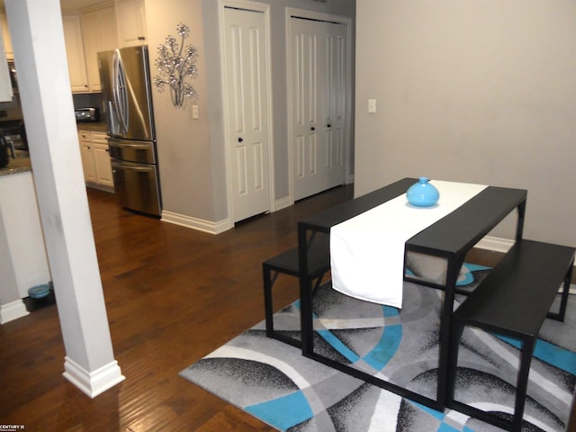 dining area featuring dark wood-type flooring and baseboards