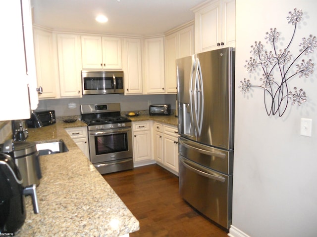 kitchen featuring a toaster, dark wood-style floors, appliances with stainless steel finishes, light stone countertops, and recessed lighting