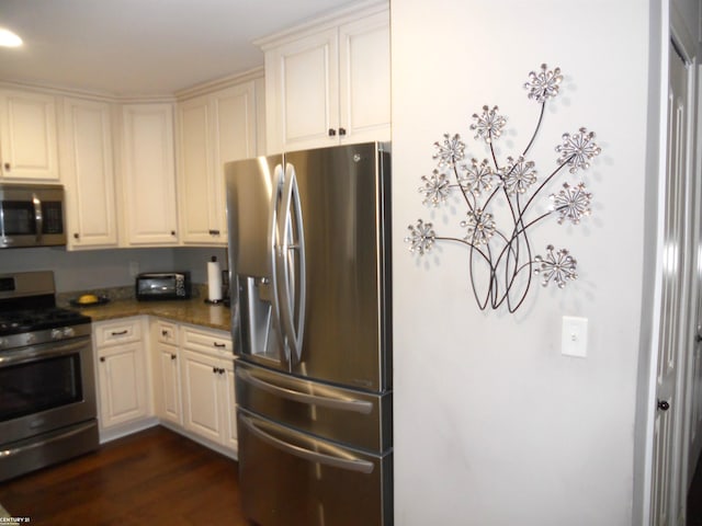 kitchen featuring appliances with stainless steel finishes, dark stone counters, and dark wood-type flooring