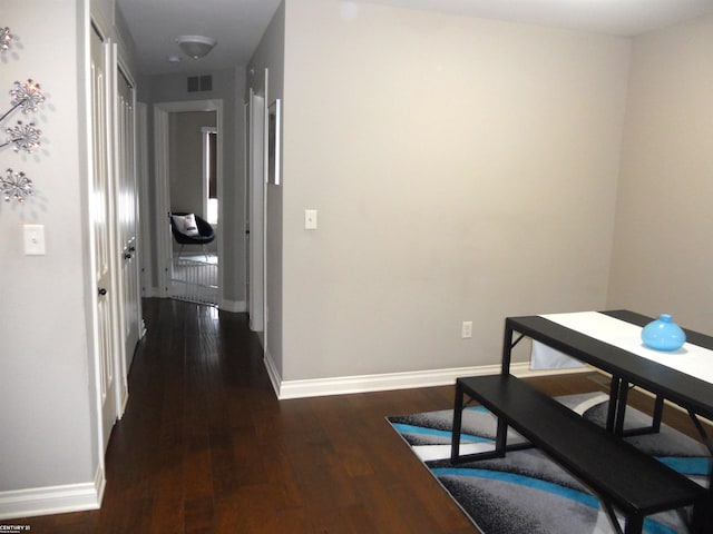 hall with baseboards, visible vents, and wood finished floors