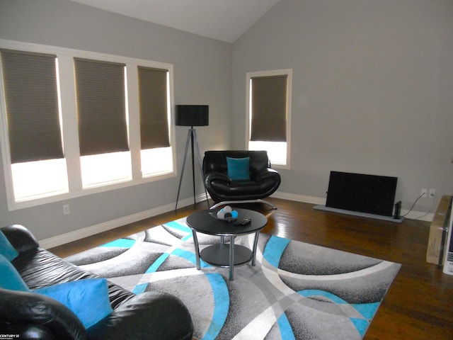 living area with lofted ceiling, wood finished floors, and baseboards