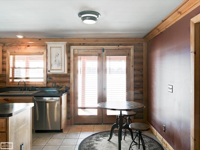 kitchen featuring light tile patterned floors, stainless steel dishwasher, a sink, and a wealth of natural light