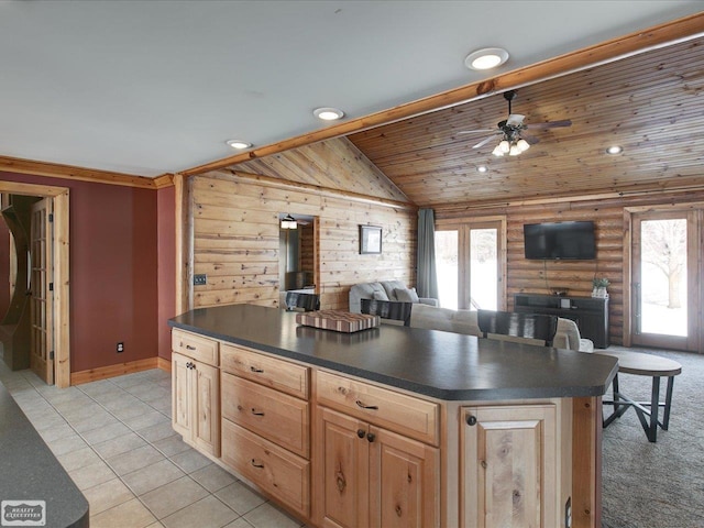 kitchen with log walls, dark countertops, light brown cabinetry, open floor plan, and vaulted ceiling