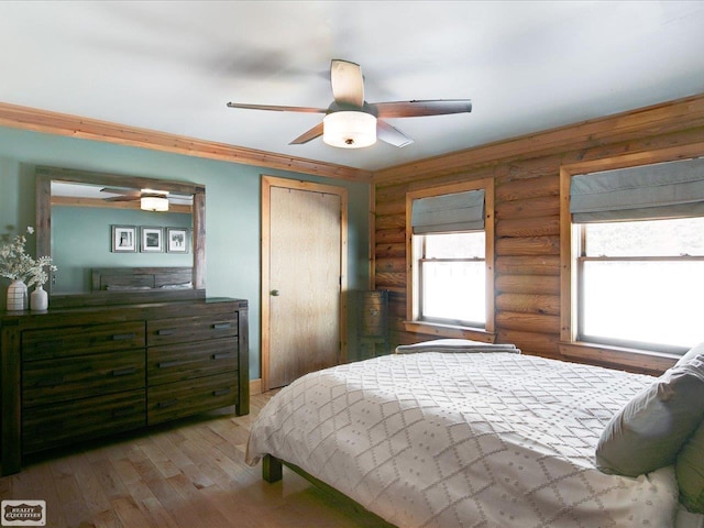 bedroom with rustic walls, light wood-style flooring, and a ceiling fan