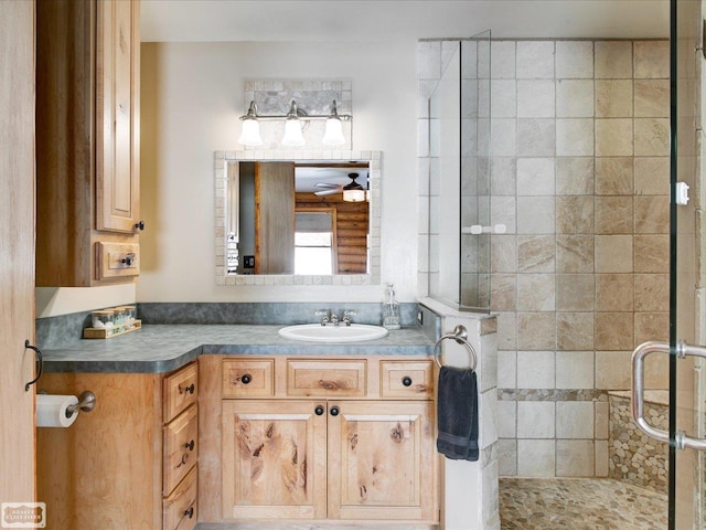 full bathroom with a stall shower, ceiling fan, and vanity