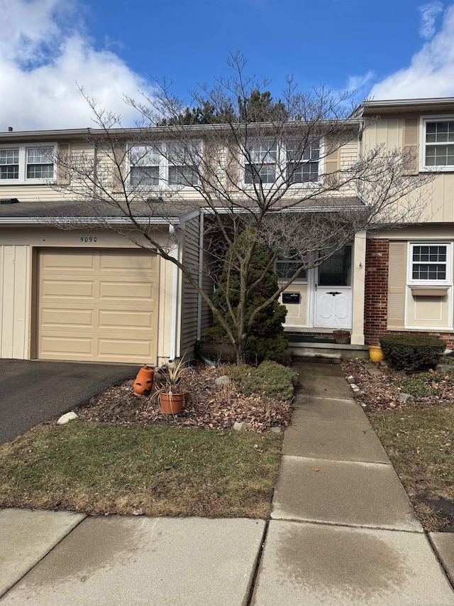 multi unit property featuring aphalt driveway, brick siding, and an attached garage