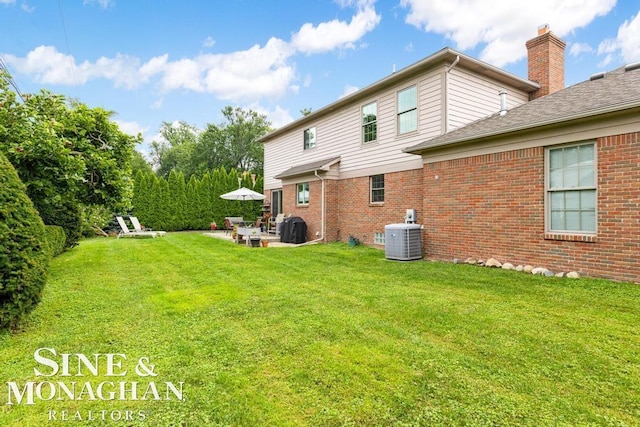 back of house with a yard, a patio area, central AC, and brick siding