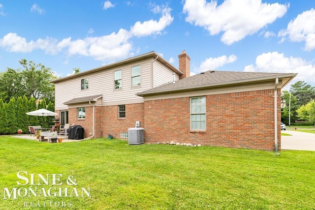 rear view of house featuring a yard, a patio, cooling unit, and brick siding