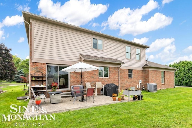 rear view of house featuring a patio, brick siding, a lawn, and central air condition unit