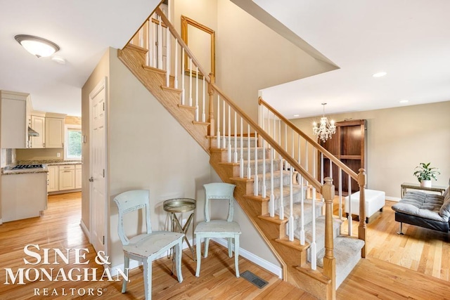 staircase featuring baseboards, visible vents, wood finished floors, a chandelier, and recessed lighting