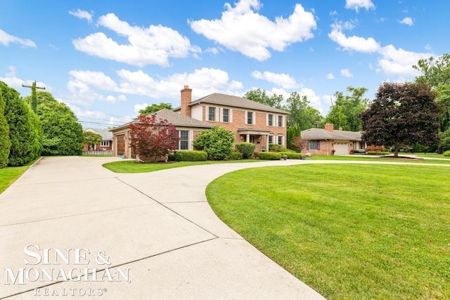 view of front facade featuring a front lawn, curved driveway, a chimney, and brick siding