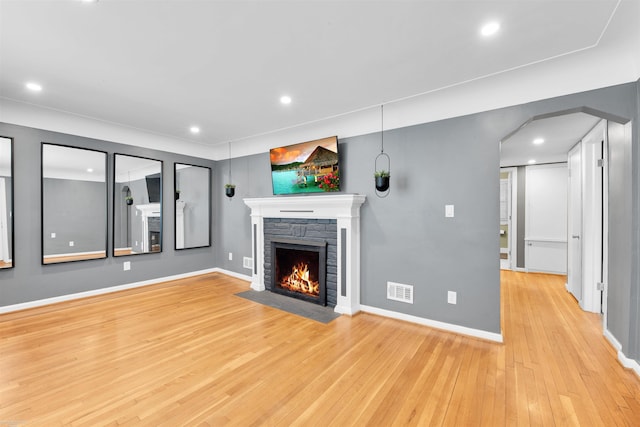 unfurnished living room with baseboards, a fireplace, visible vents, and wood finished floors