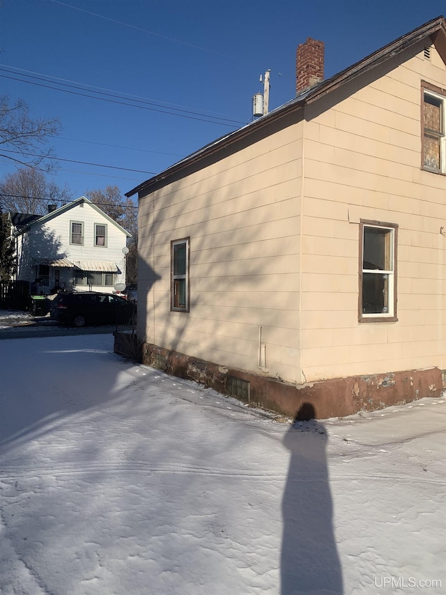 view of snow covered exterior with a chimney