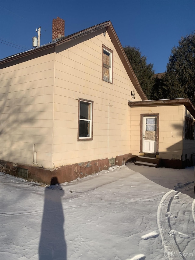 rear view of house featuring entry steps and a chimney