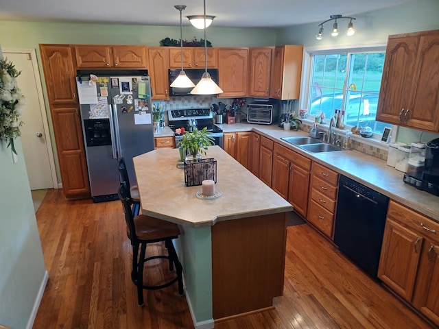 kitchen with wood finished floors, a sink, light countertops, appliances with stainless steel finishes, and backsplash