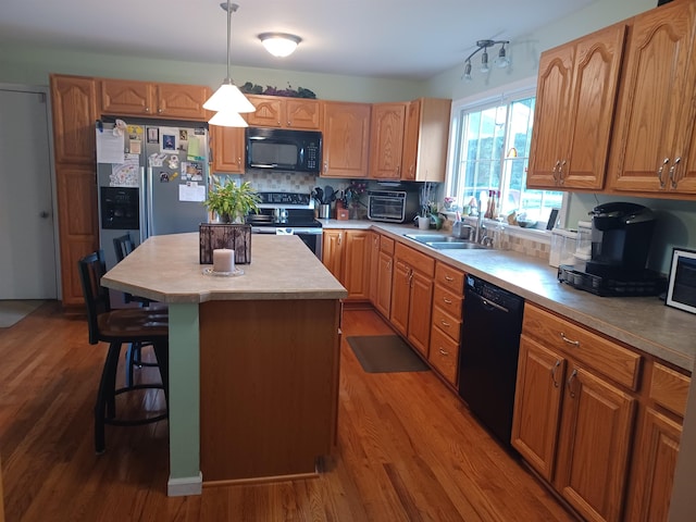 kitchen with tasteful backsplash, a kitchen island, wood finished floors, black appliances, and a sink