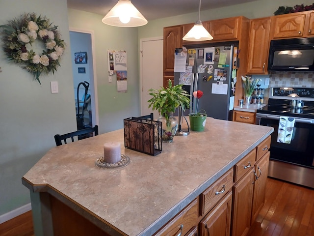 kitchen featuring dark wood finished floors, a kitchen island, appliances with stainless steel finishes, pendant lighting, and backsplash