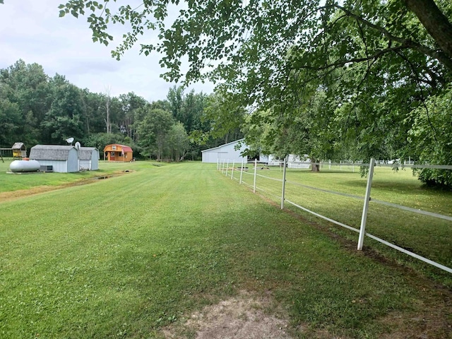 view of yard with a rural view, fence, and an outbuilding