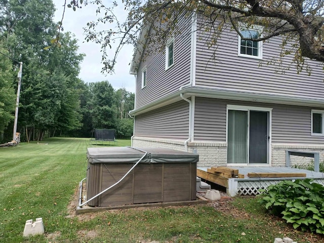 view of side of property with a deck, a yard, and a hot tub