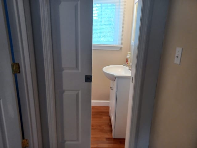 bathroom featuring baseboards, wood finished floors, and vanity