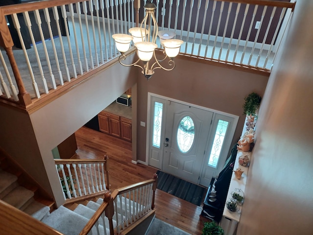 entryway with a chandelier, stairway, wood finished floors, and a towering ceiling