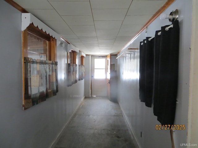 corridor featuring a paneled ceiling and baseboards