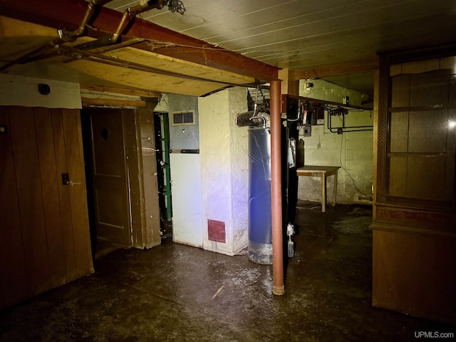 unfinished below grade area featuring water heater, visible vents, and concrete block wall