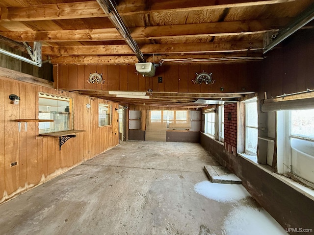 miscellaneous room with a garage, a healthy amount of sunlight, concrete floors, and wooden walls