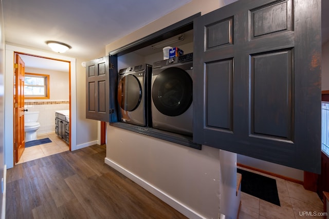 laundry area with laundry area, tile patterned flooring, tile walls, and independent washer and dryer