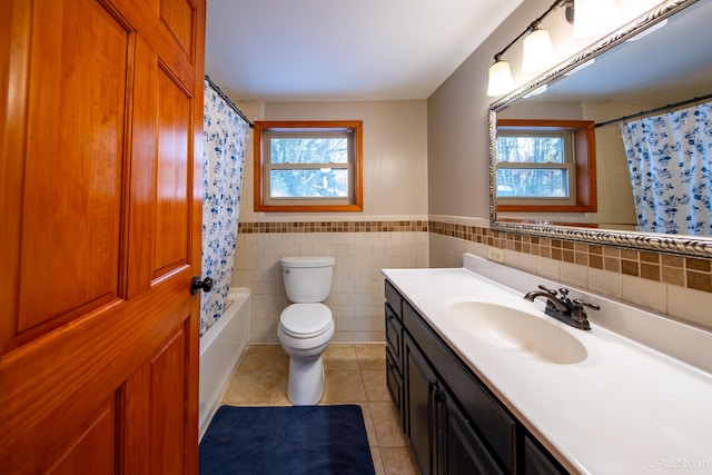 bathroom featuring a wainscoted wall, tile walls, toilet, vanity, and tile patterned flooring