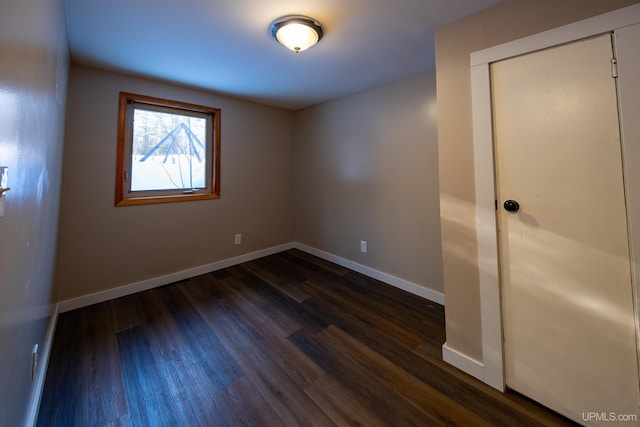 unfurnished bedroom featuring a closet, baseboards, and dark wood-type flooring