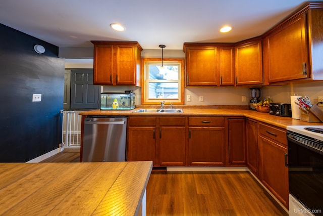 kitchen with range with electric cooktop, dark wood finished floors, light countertops, stainless steel dishwasher, and a sink