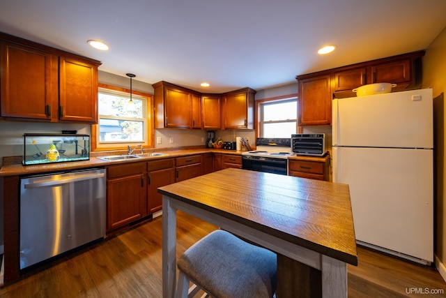 kitchen with dark wood-style flooring, stainless steel dishwasher, freestanding refrigerator, a sink, and range with electric cooktop