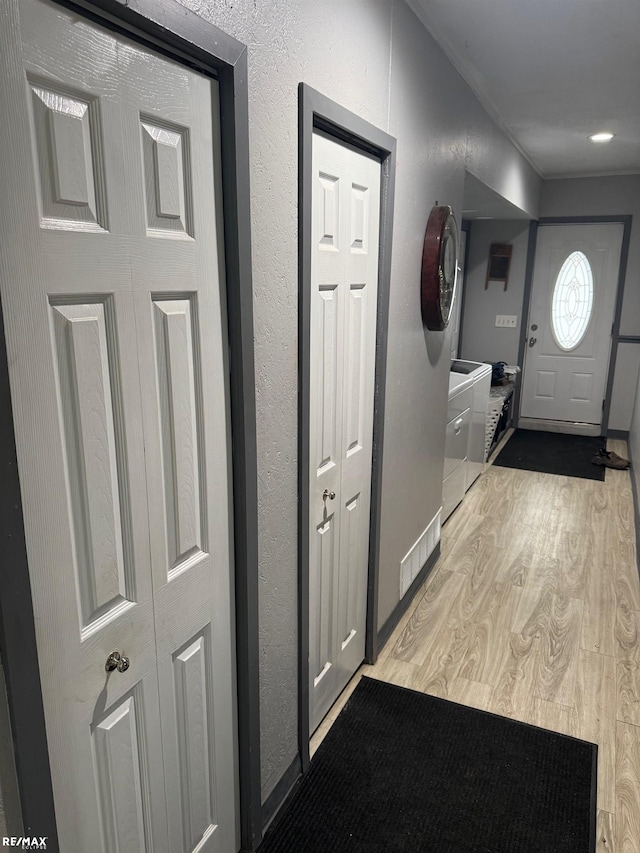 hall with light wood finished floors and a textured wall