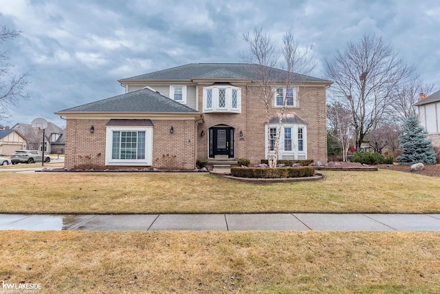 view of front of house featuring brick siding, roof with shingles, and a front yard