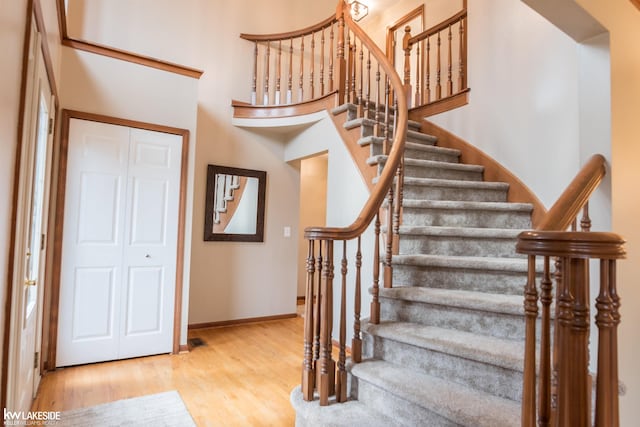 foyer with a towering ceiling, stairway, baseboards, and wood finished floors