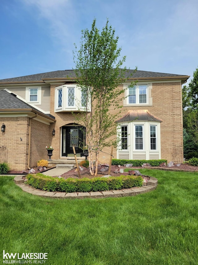 view of front facade featuring brick siding and a front yard