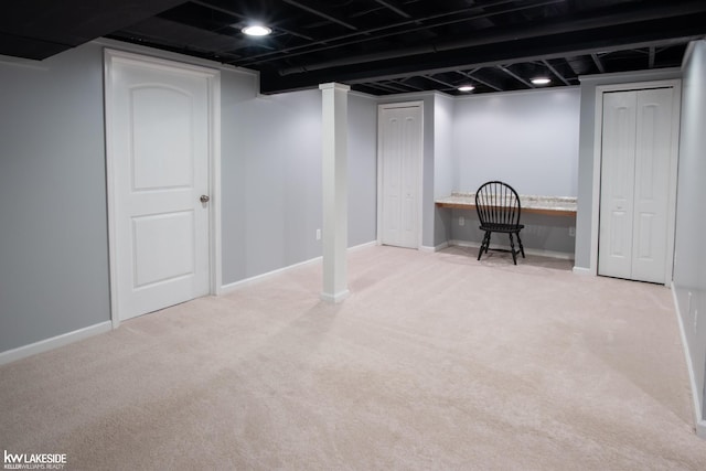 finished below grade area with carpet floors, built in desk, and baseboards