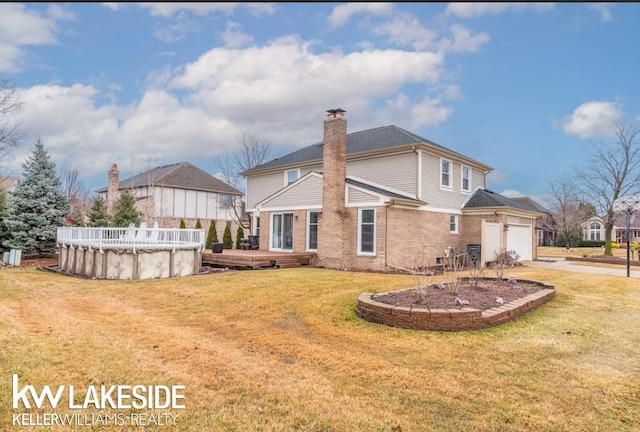 back of property with a garage, driveway, a yard, a covered pool, and a chimney