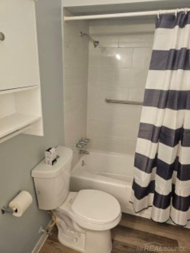 bathroom with shower / bath combo, wood finished floors, and toilet