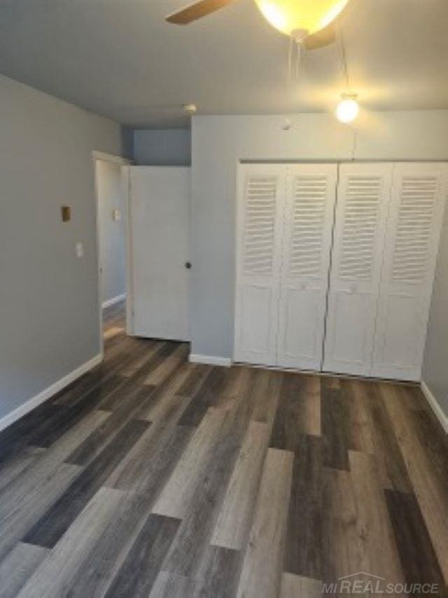 unfurnished bedroom with a closet, baseboards, and wood finished floors