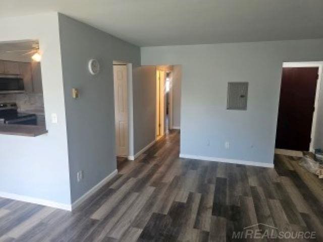 interior space featuring wood finished floors, electric panel, and baseboards