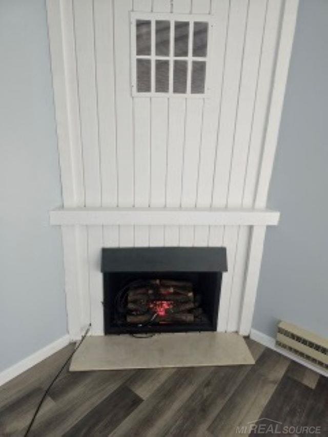 details featuring wood finished floors, a fireplace with flush hearth, and baseboards