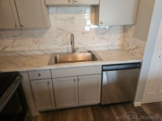 kitchen featuring tasteful backsplash, dark wood finished floors, stainless steel appliances, and a sink