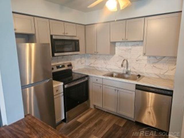 kitchen featuring stainless steel appliances, a sink, light countertops, gray cabinets, and backsplash