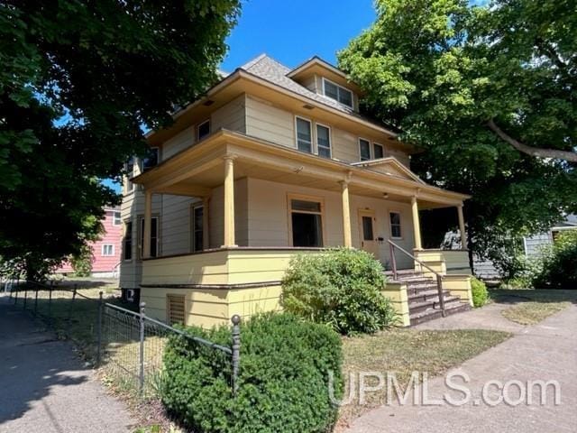 american foursquare style home featuring fence and a porch