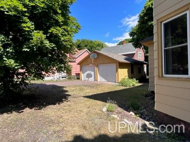 view of side of home featuring a garage, a yard, and an outdoor structure